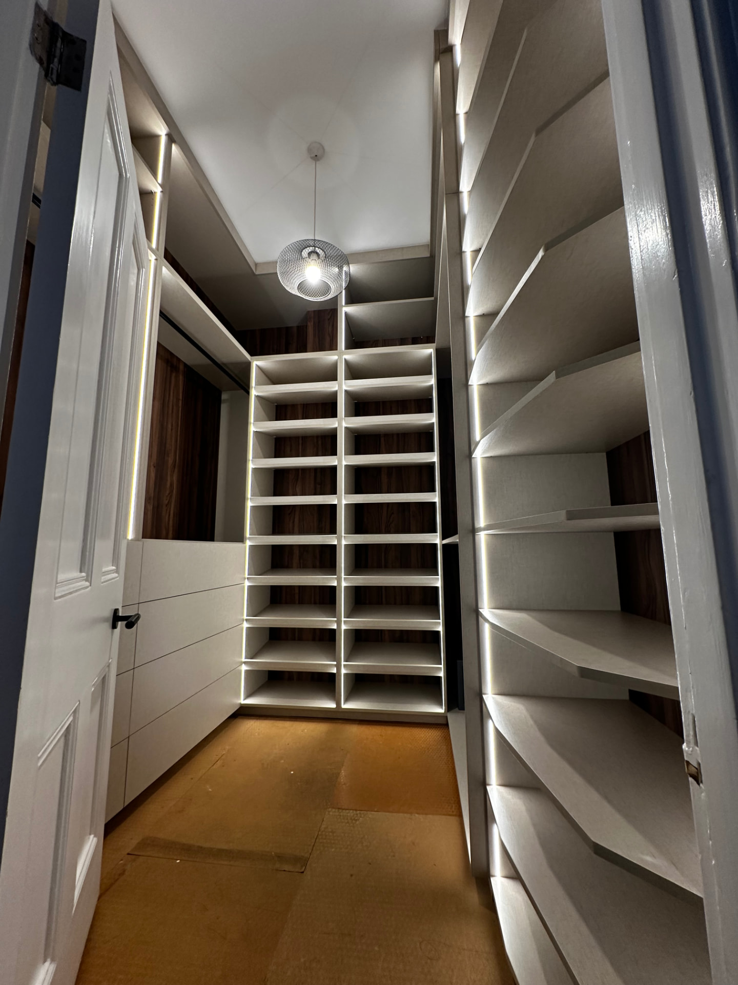 Illuminated bespoke dressing room with open shelving and drawers